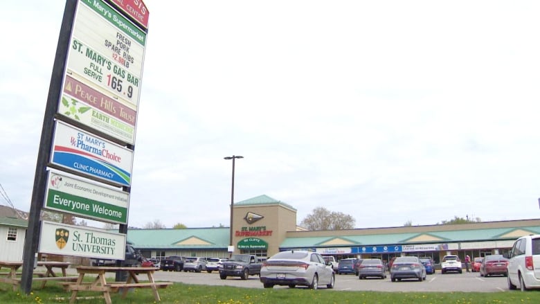 A shopping plaza with a parking lot in front with parked cars.