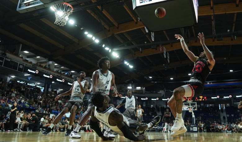 Calgary Surge's Sean 'Rugzy' Miller-Moore, right, shoots over a falling Scarborough Shooting Stars' Myck Kabongo, front left, during the first half of the CEBL basketball championship final, in Langley, B.C.