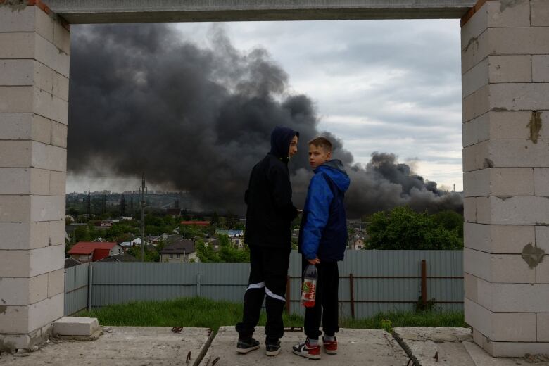 Teenagers talk as they look at smoke rising after a missile strike.