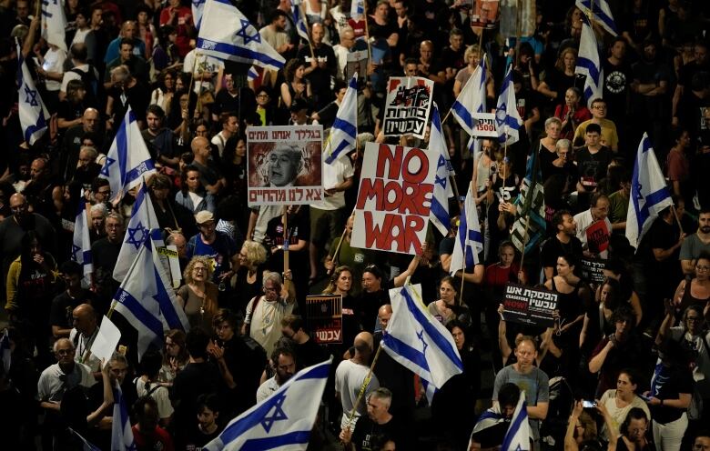 Protesters hold Israeli flags and a sign reading 