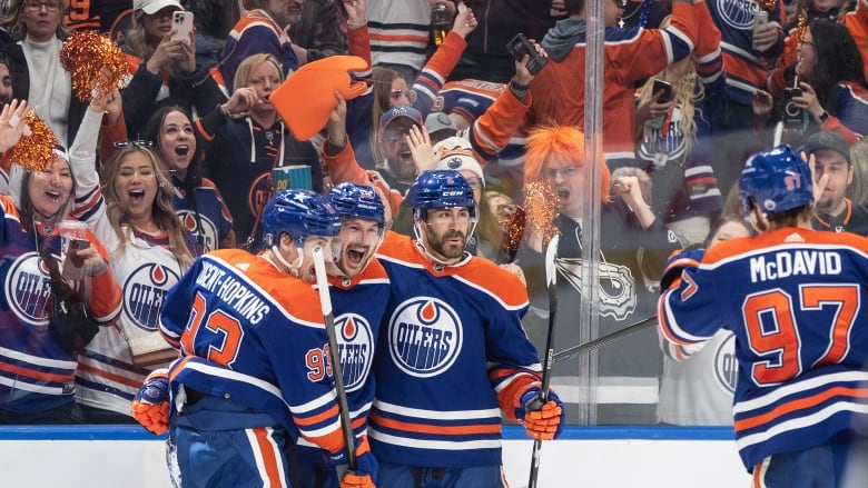 Hockey players celebrate a goal as onlookers cheer from the stands