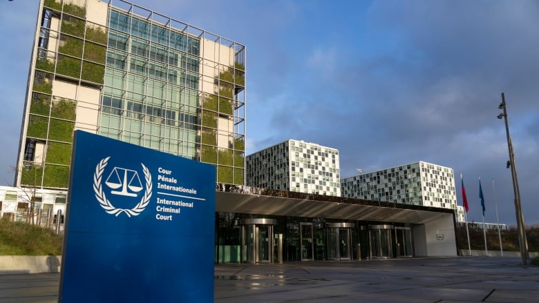 An exterior view of three connected buildings with a blue sign in front reading 