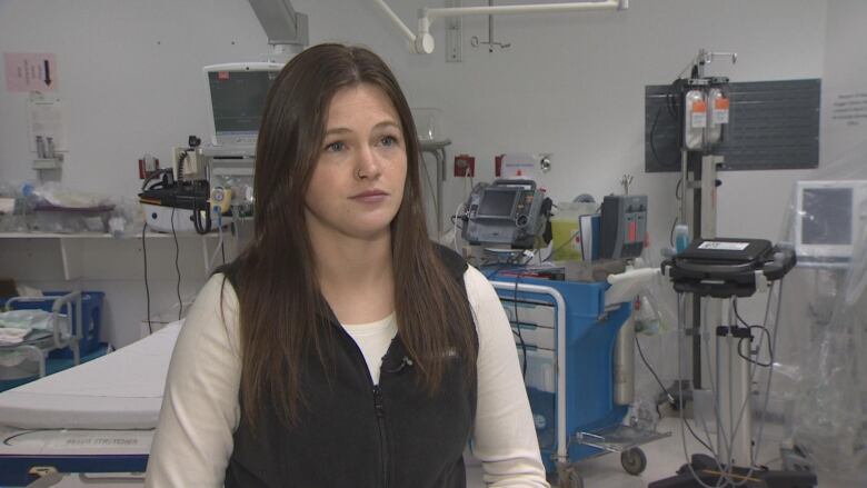 A nurse wearing black and white standing in an emergency room