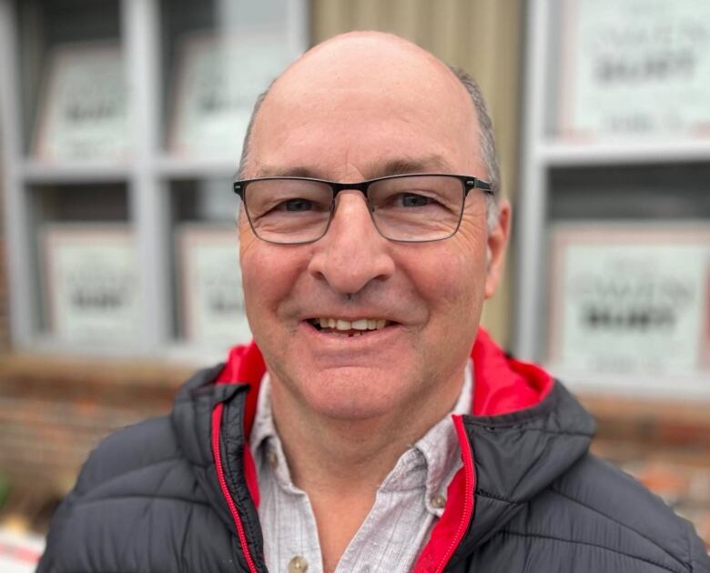 Man with glasses, smiling and wearing a puffy jacket