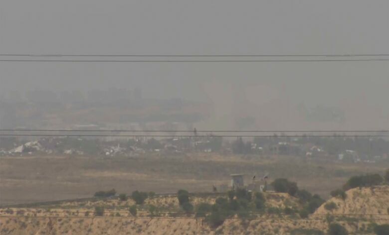 A hazy view of Gaza with electrical wires running across image. 