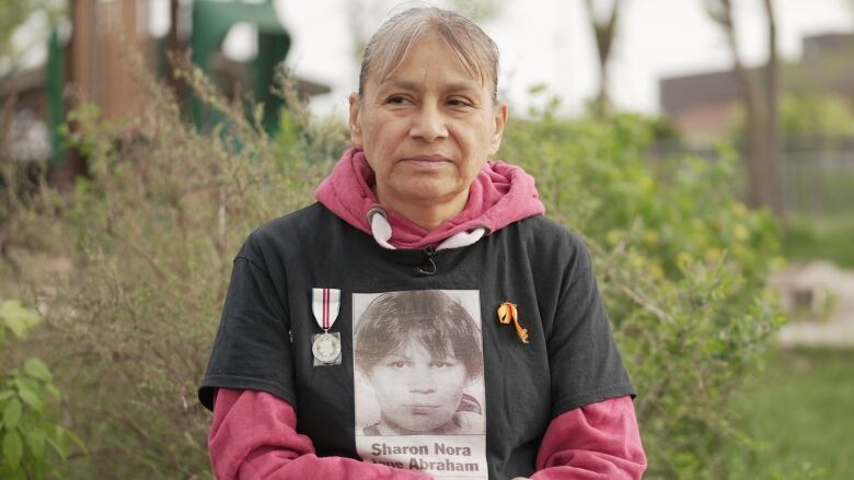 A woman is pictured looking to her side, wearing a shirt with an image of a missing woman.