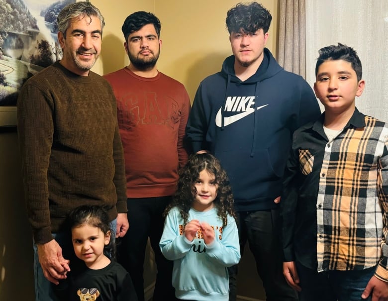 Wali Mohammad Dawari stands with five of his seven children in the living room of their Calgary home. 