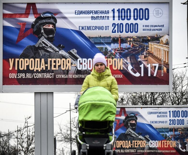 A woman in St. Petersburg, Russia, pushes a stroller past posters promoting contract service with the army.