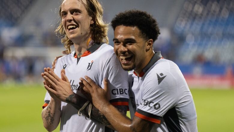 Two sweaty soccer players embrace. 