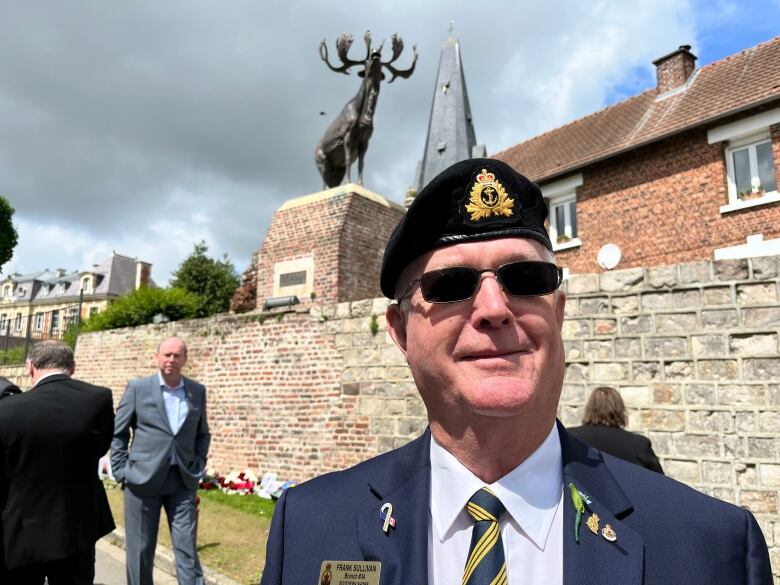 a legion member and veteran, frank sullivan, poses in front of a war memorial in northern france.