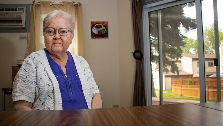 An old woman sits at a table.