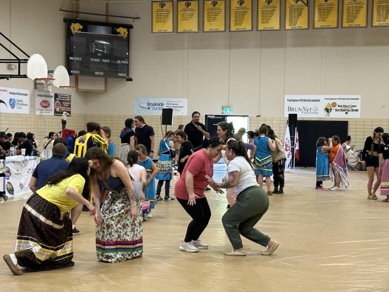 People gather in pairs inside a gymnasium for an Indigenous potato dance.