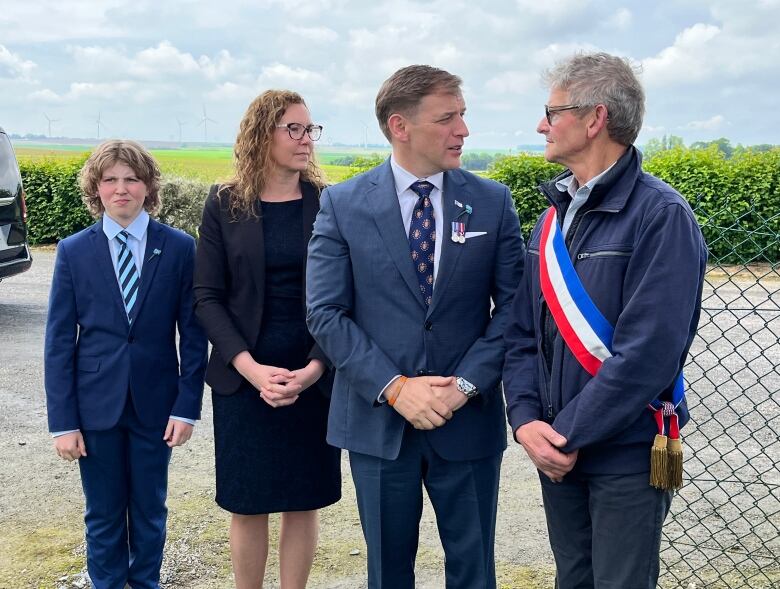 a group of people standing formally at a war memorial 