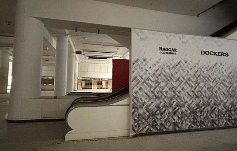 The escalators and empty floors of a vacant department store are seen from inside.