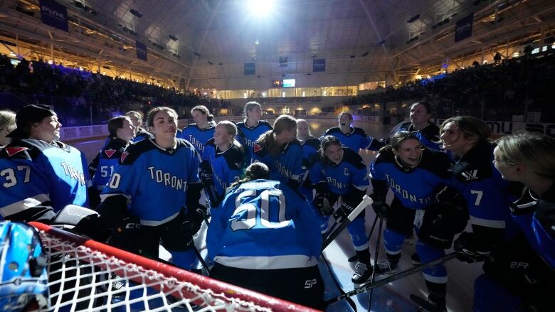 Hockey players huddle around net before a game