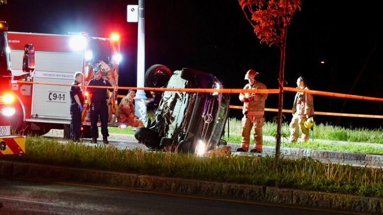 Police and firefighters examine the site of a car crash. 