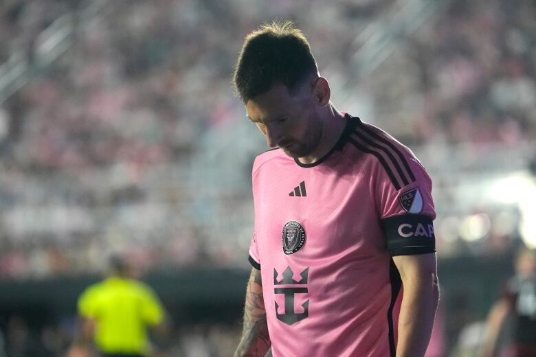 A soccer player wearing pink looks down.