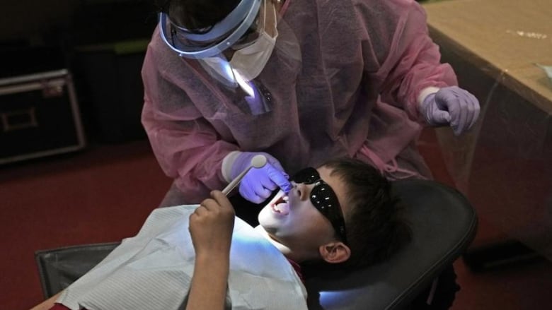 A dentist performs an examination of a child's teeth.