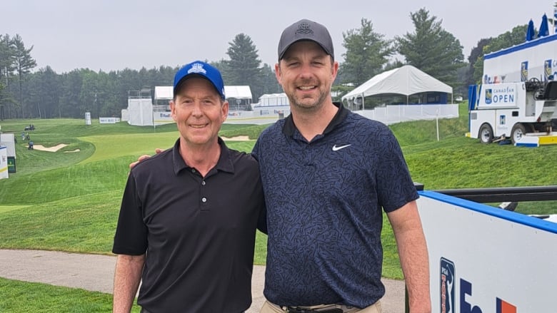 Two men in golf attire stand next to each other smiling on a golf course