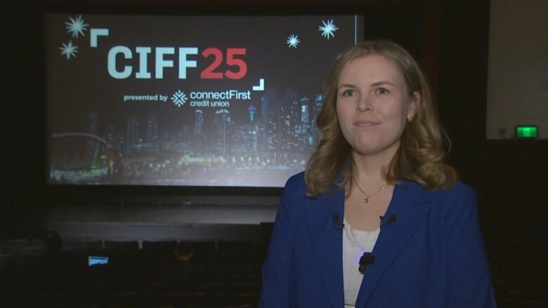 A blonde woman smiles in front of the camera