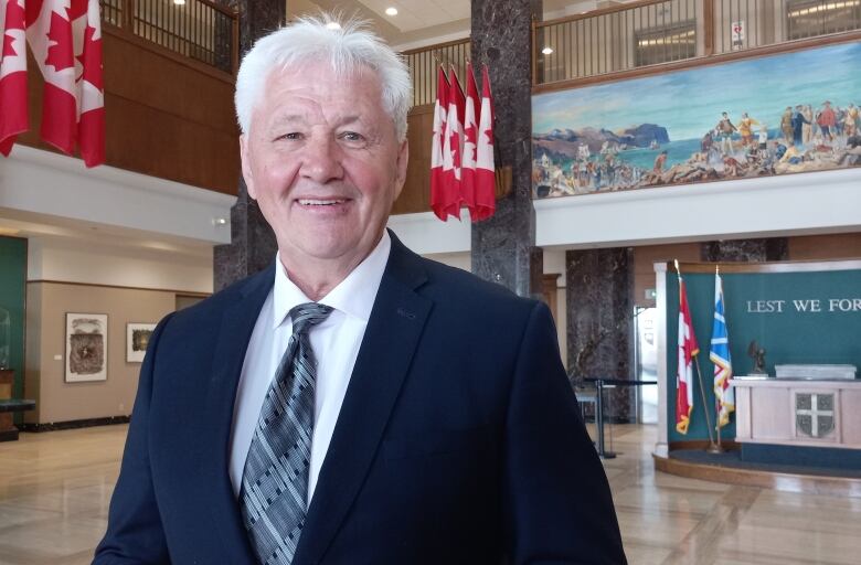 Man with short cut white hair in suit.