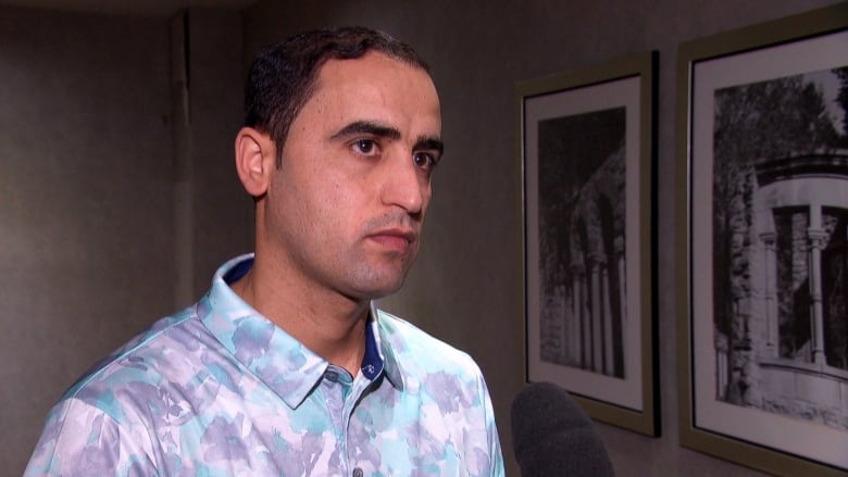 A man wearing a patterned shirt looks at the camera. 