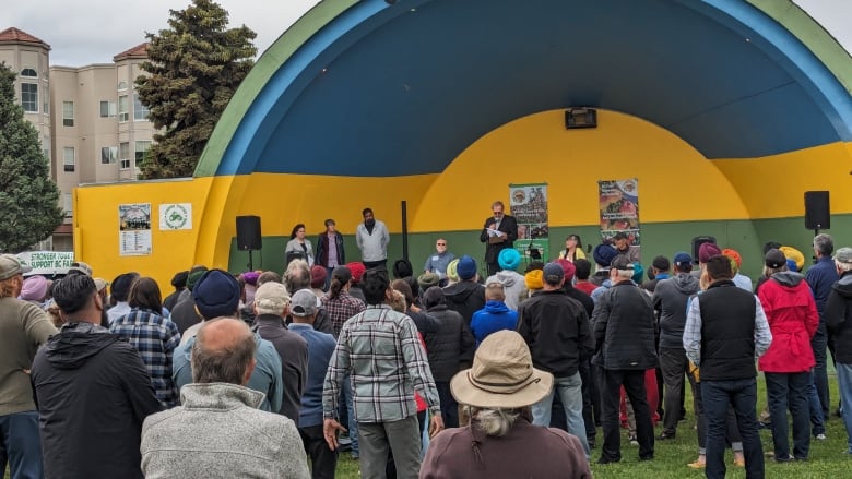 A man speaks on a stage in front of a crowd.