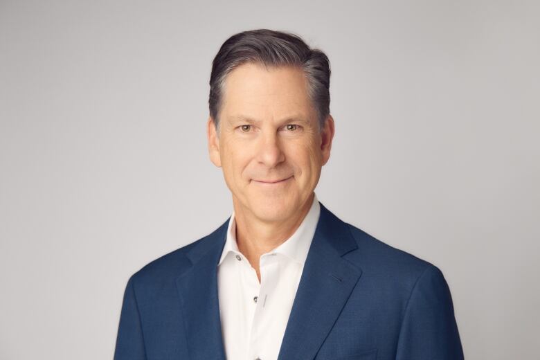 A man with greying hair in a blue suit