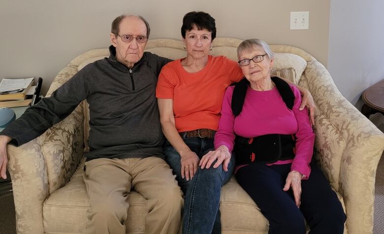 Three people sitting on a couch.