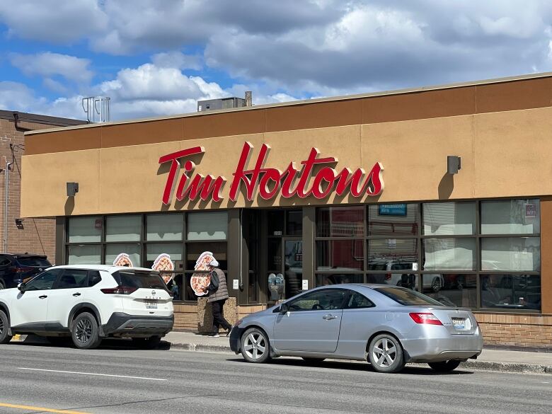 Cars are seen parked on the street in front of a Tim Hortons restaurant.