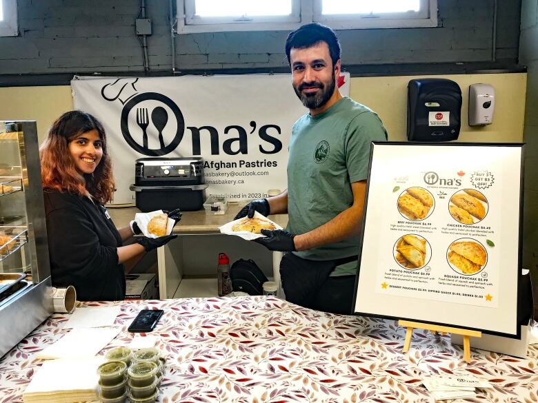 A woman and a man hold up a couple of Afghani hand pies called pouchak.