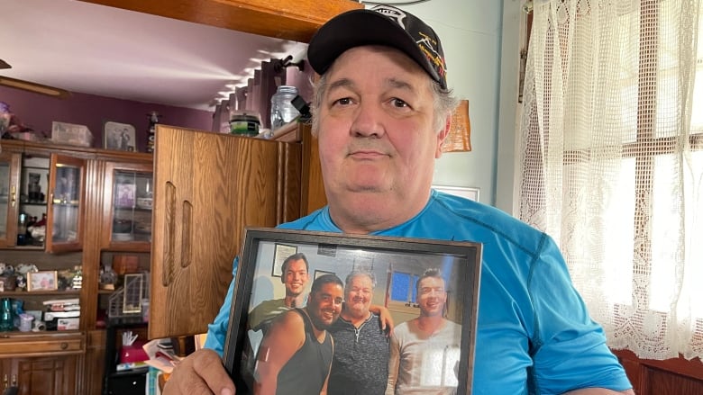 A man holds a framed photograph.