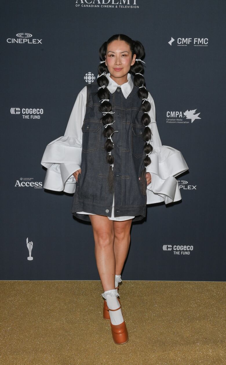 Elaine Lui on the red carpet wearing a white shirt dress with oversized sleeves with a denim top layer.