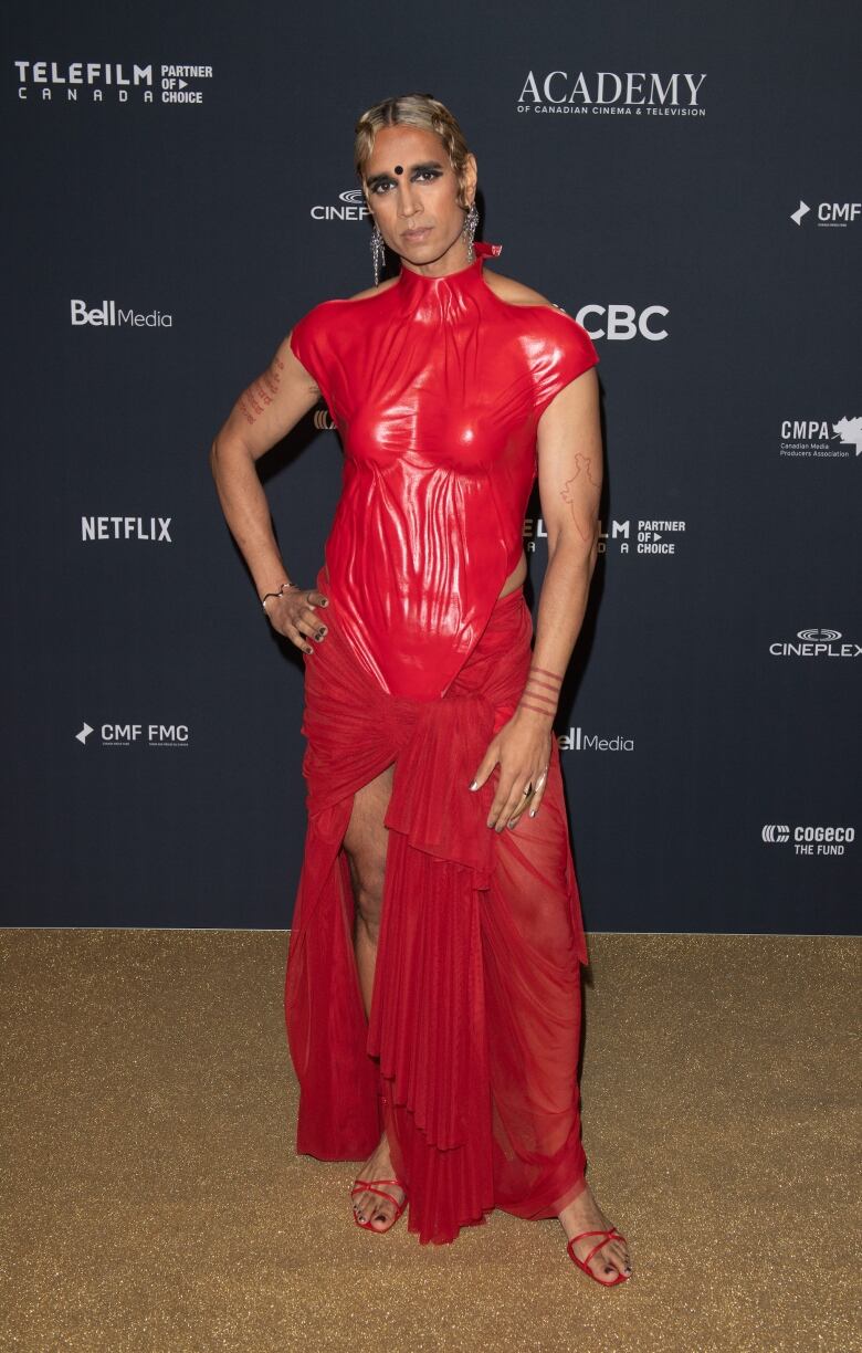 Vivek Shraya on the Canadian Screen Awards red carpet wearing a fitted red dress. 