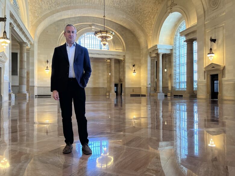 Man standing indoors in wide open space in a renovated train station.