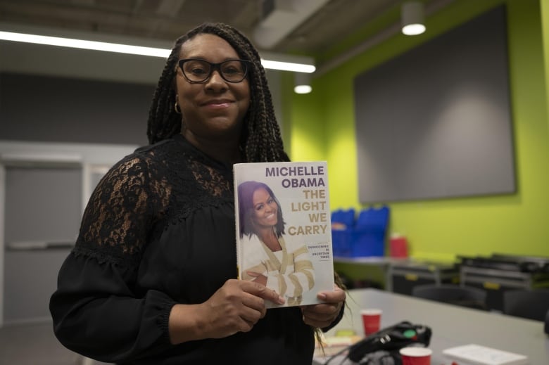 Amie Archibald-Varley holds up a copy of Michelle Obama's The Light We Carry.