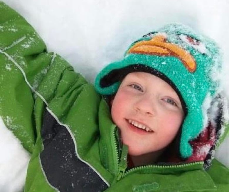 Landyn Davis lies in the snow in a green jacket.