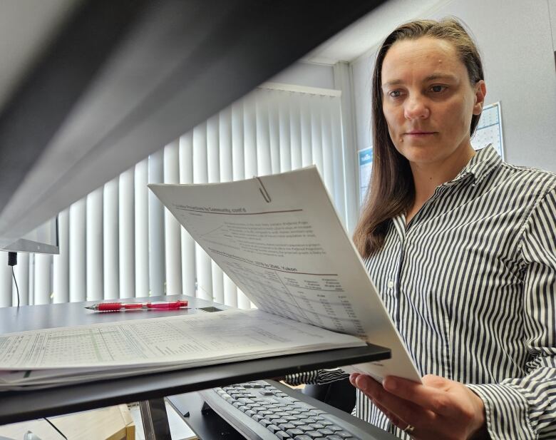 Person standing at a computer looking at a report. 