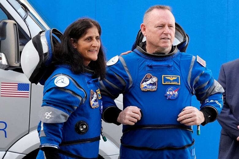 Two people in astronaut gear are pictured. 