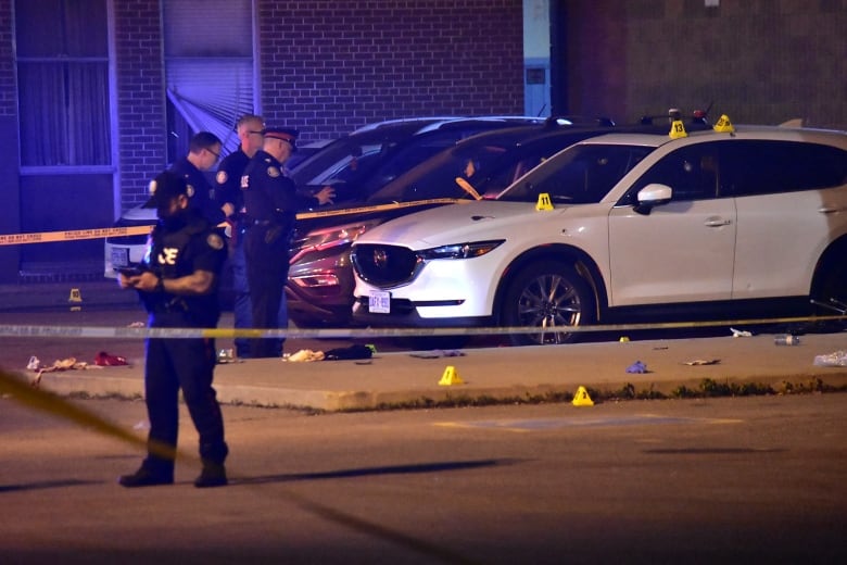 Toronto police at the scene of a fatal shooting in the parking lot of an Etobicoke high school late Sunday.