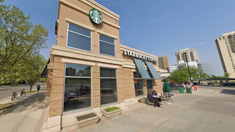 Exterior of a building with awnings and people sitting at small tables.