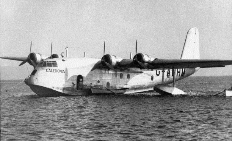 A four-engine propeller plane sitting on the water.