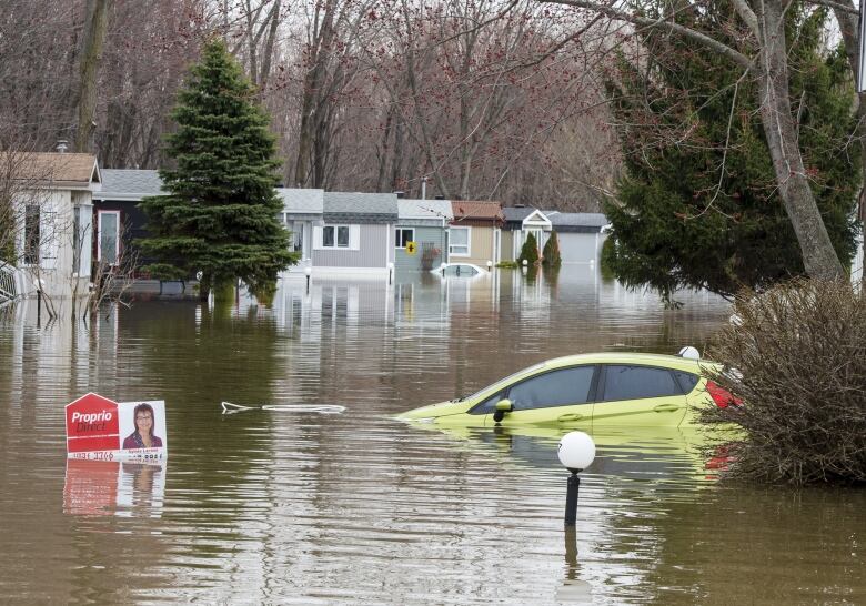 A car sits submerged in floodwater on Wednesday, May 1, 2019 in Ste-Marthe-sur-la-Lac, Que.