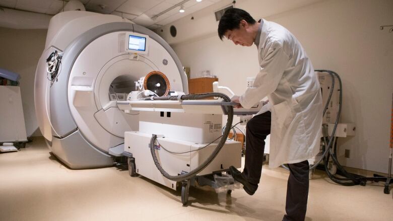 A man stands next to an MRI machine.