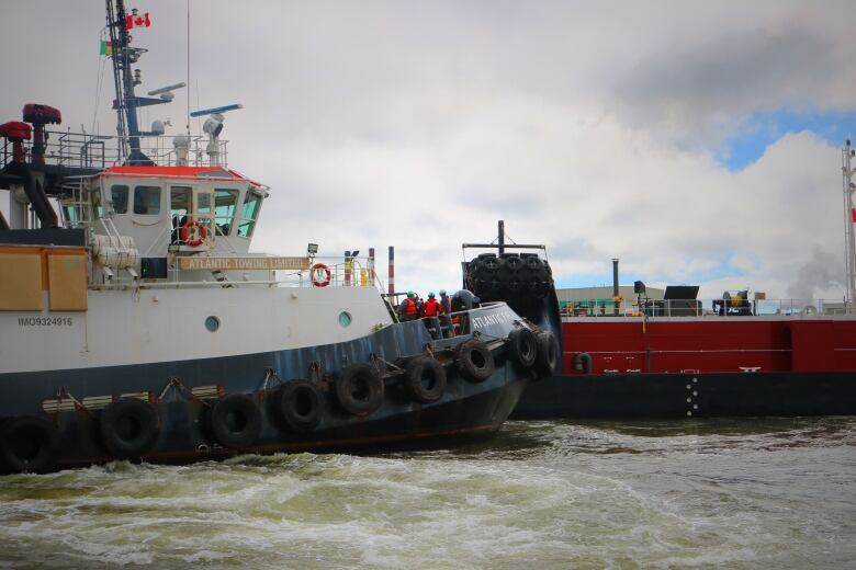 A tugboat pushes against a large barge undocking in Courtenay Bay. 