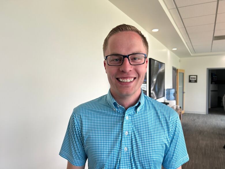 A man in a blue gingham shirt in a boardroom.