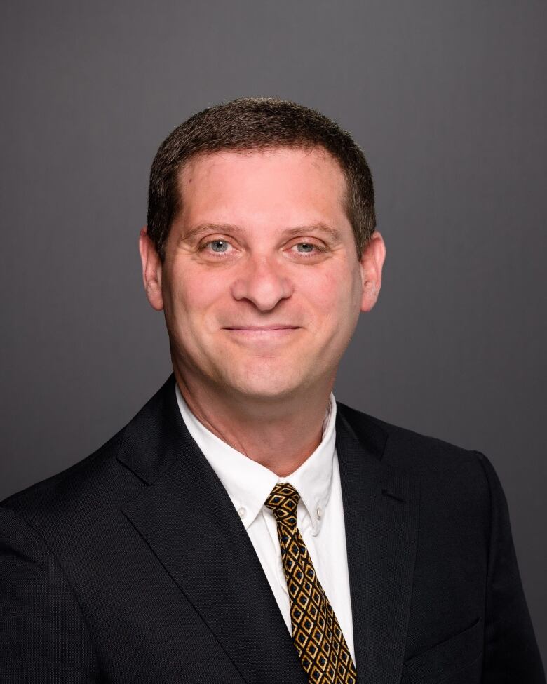 A headshot of a man wearing a suit.