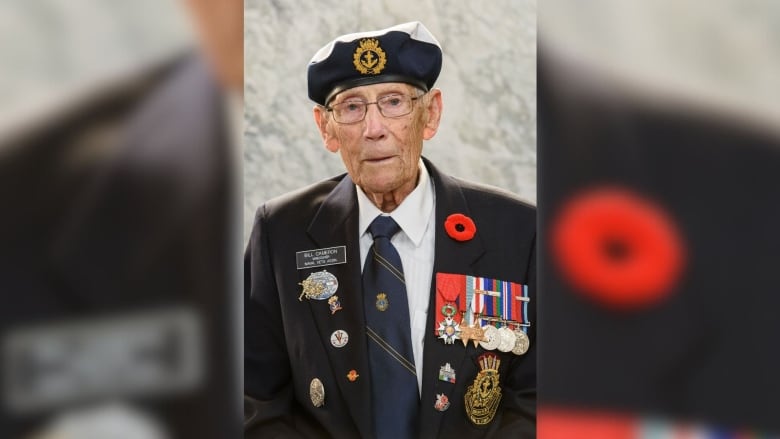 An older man with various military medals stands for a headshot.