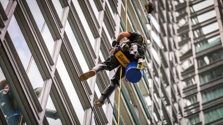 A window washer is shown suspended from a building.