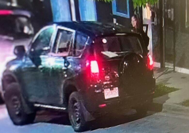 A black SUV parked near a small tree.